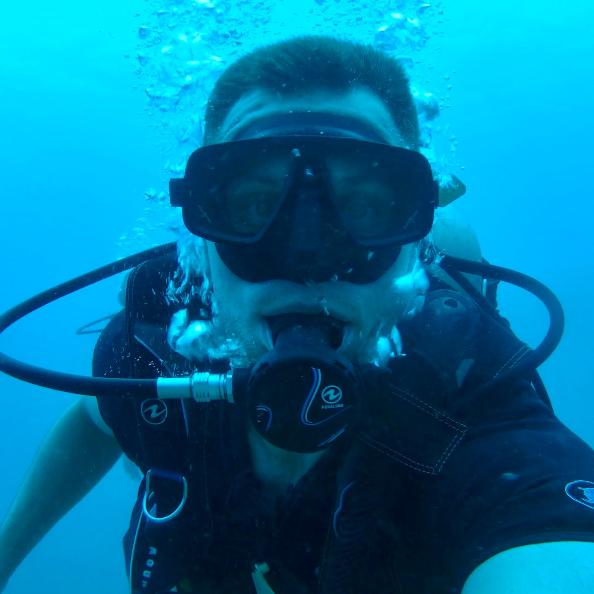 Person scuba diving underwater wearing a mask and tank